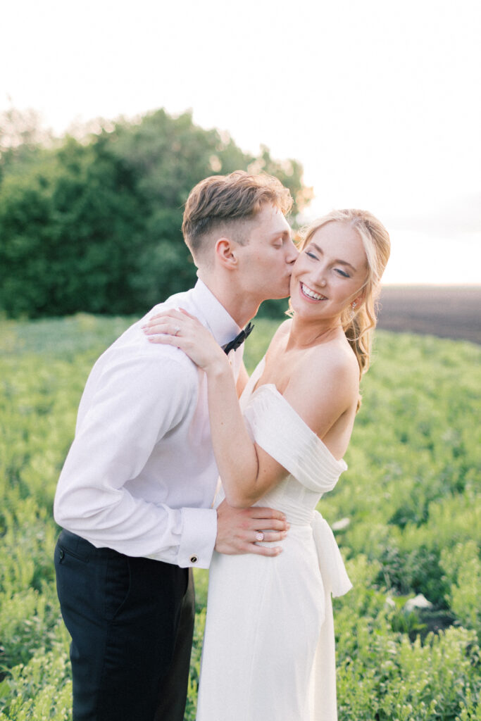 groom kissing bride on the cheek 