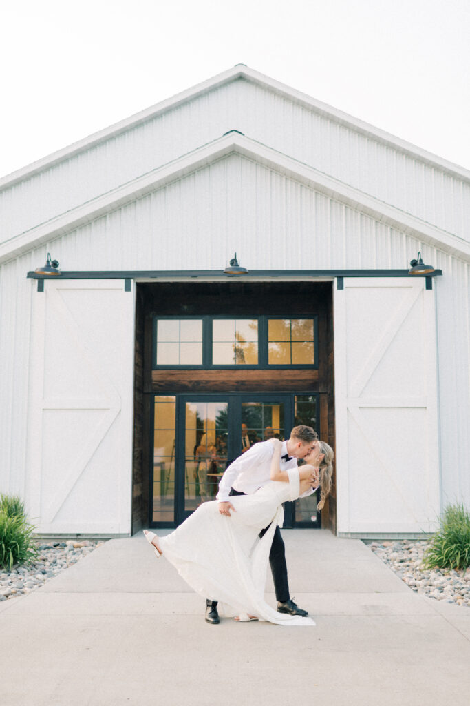 bride and groom kissing outside venue doors