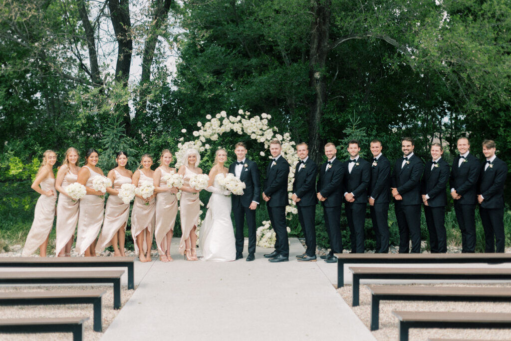 full wedding party at the alter smiling at camera; Classic Wedding Photos at The Pines White Venue outside of Fargo, ND 