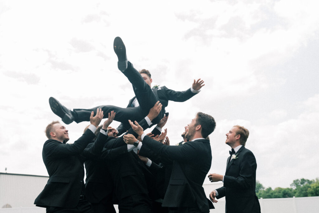 groomsmen throwing groom in the air 