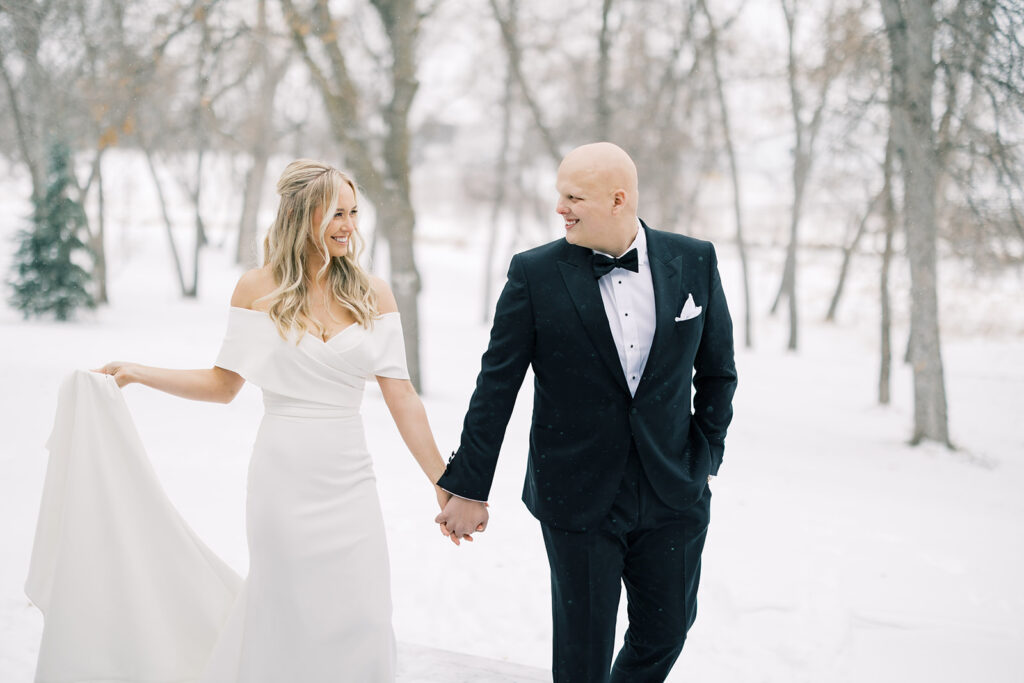bride and groom walking outside in the snow hand in hand 