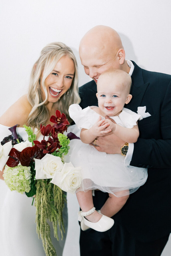 bride and groom holding flower girl