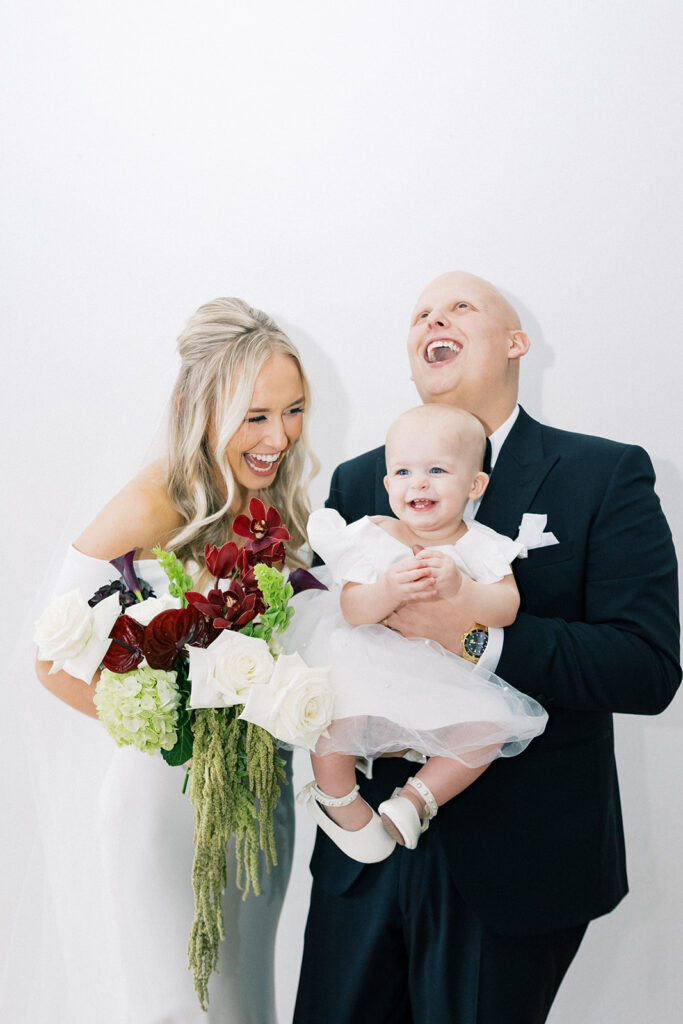 bride and groom holding flower girl