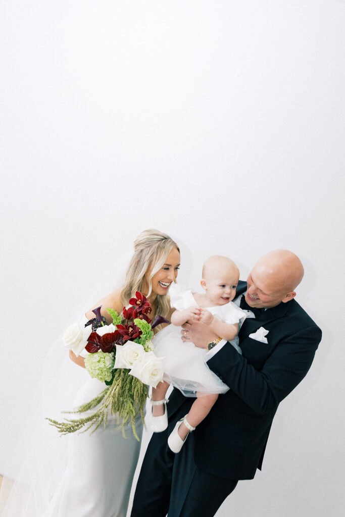 bride and groom holding flower girl