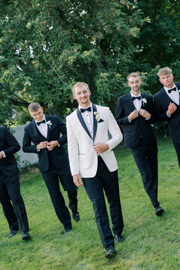 groomsmen in black tuxes, groom in white tux jacket