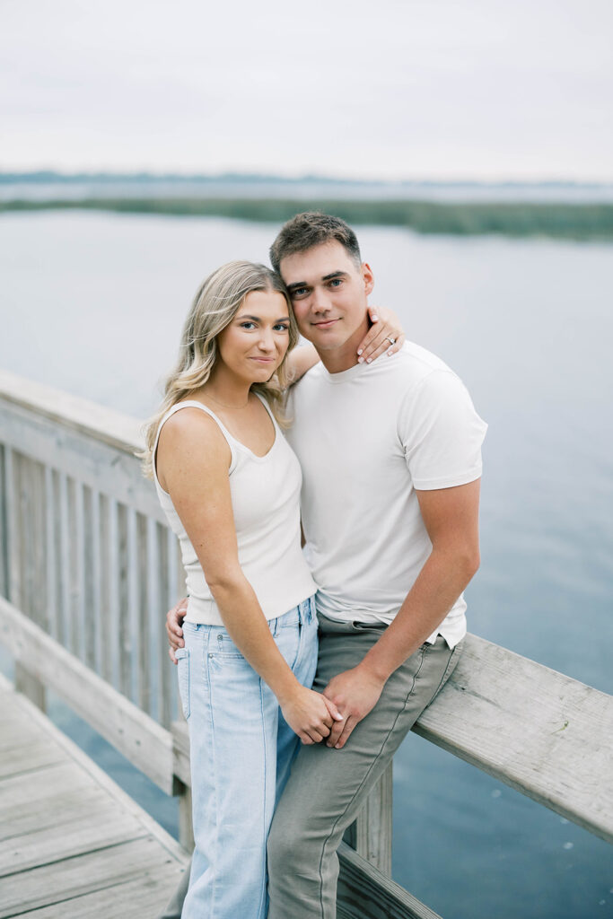 engagement session location idea, couple posing on a dock in front of a lake 
