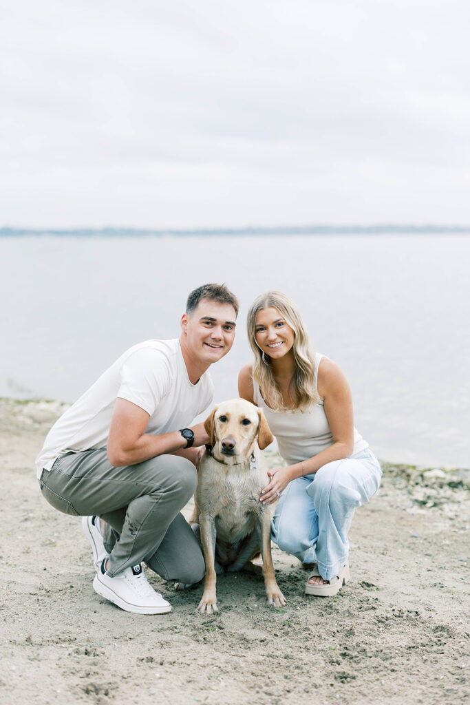 engagement session location idea, couple posing with their dog in front of a lake 