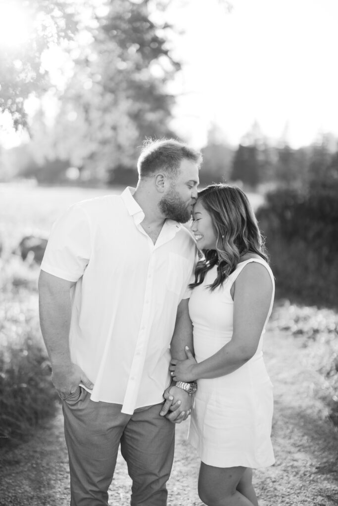 engagement session, black & white photo of a couple posing on a sunlit path surrounded by greenery