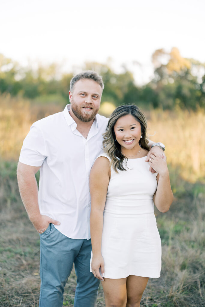 engagement session, a couple posing in a field surrounded by greenery