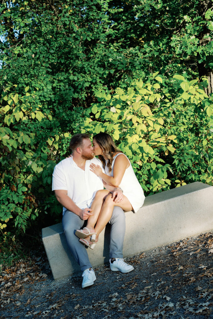 engagement session, a couple sitting in front of greenery