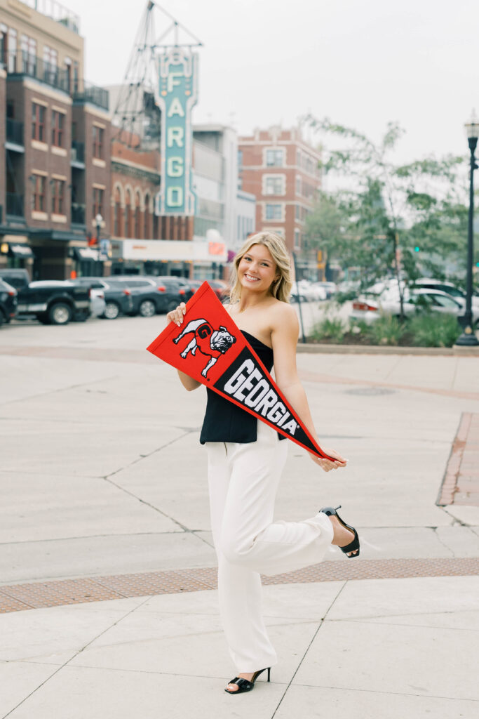 senior session, photo of a senior posing with school flag in the city