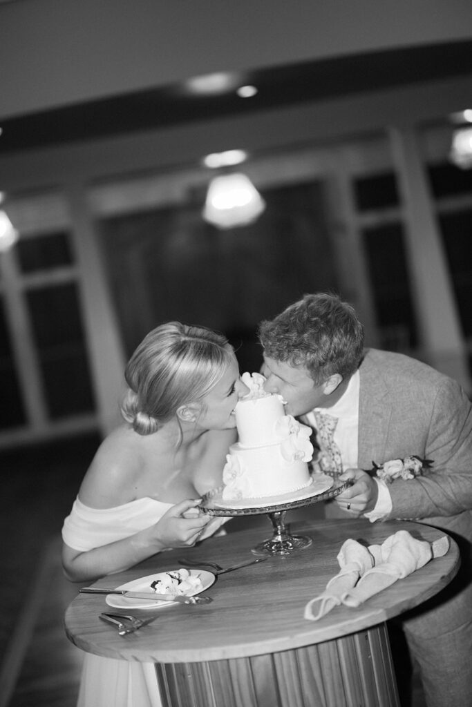 white cake with white orchids, bride and groom eating cakr