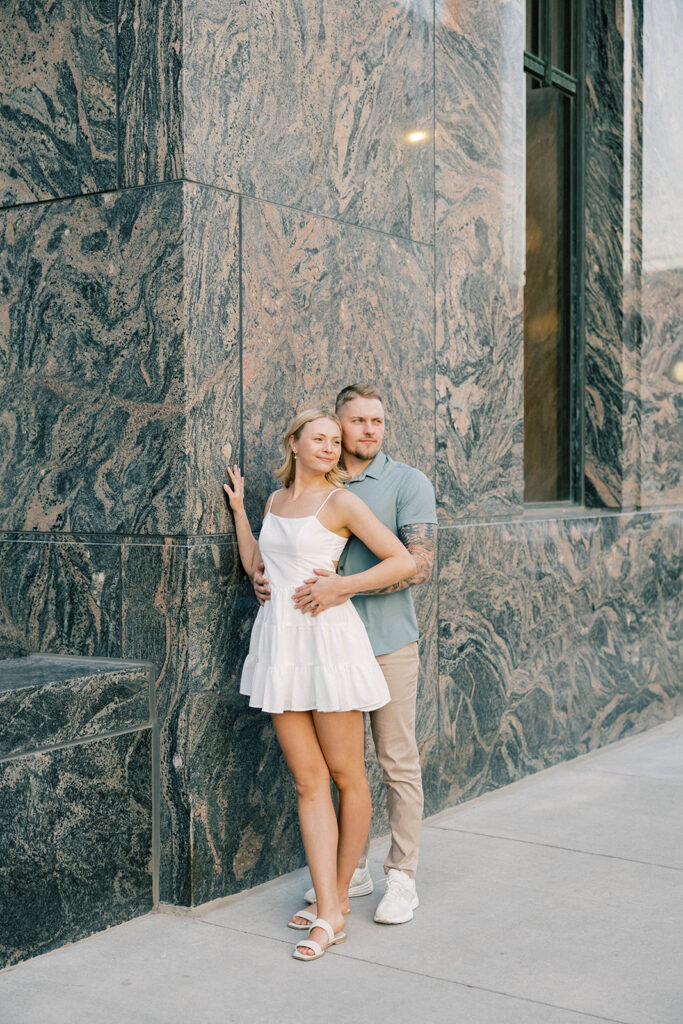 engagement session location idea, couple posing in front of a marble building downtown