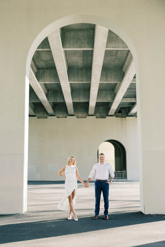 engagement session location idea, couple standing under a arch downtown