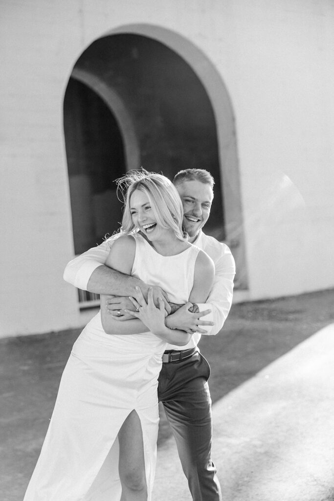 engagement session location idea, couple embracing under a arch downtown