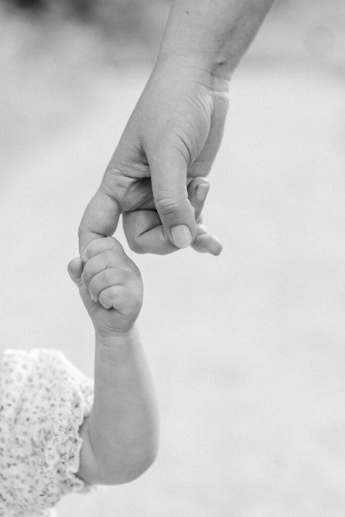 Maternity Session, black and white photo of a couple holding hands with their baby