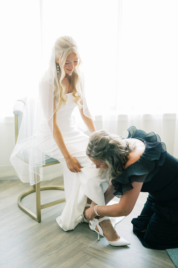mom putting on bride's shoes
