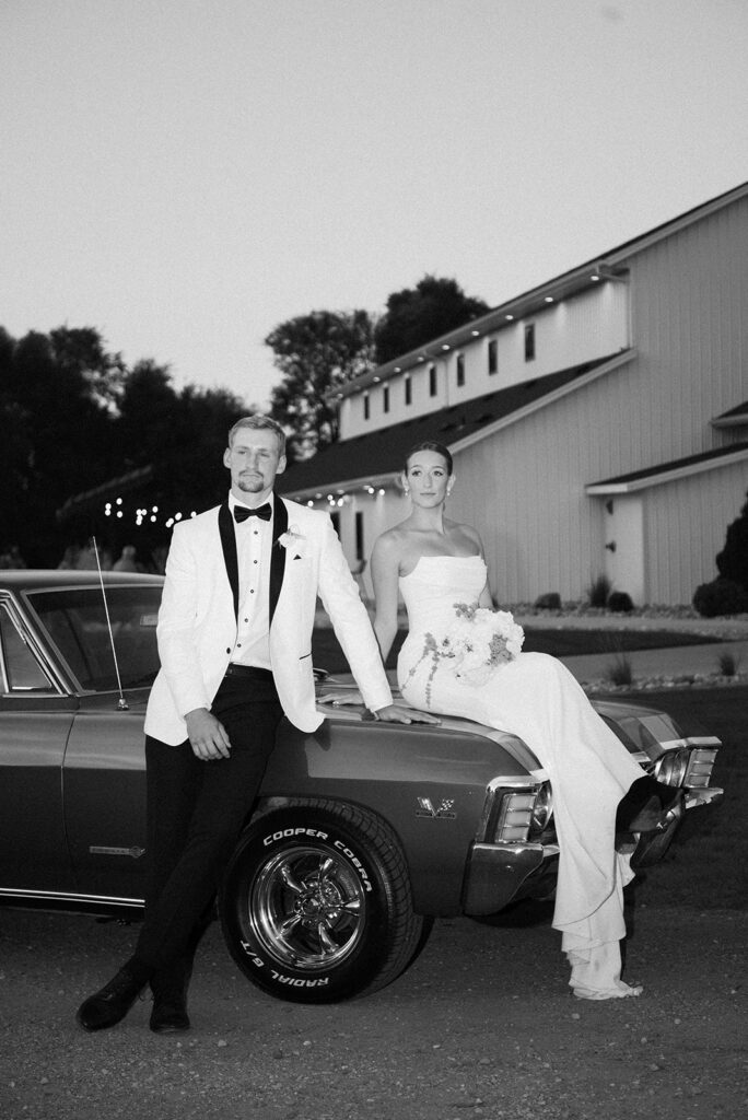 bride and groom posing on car 