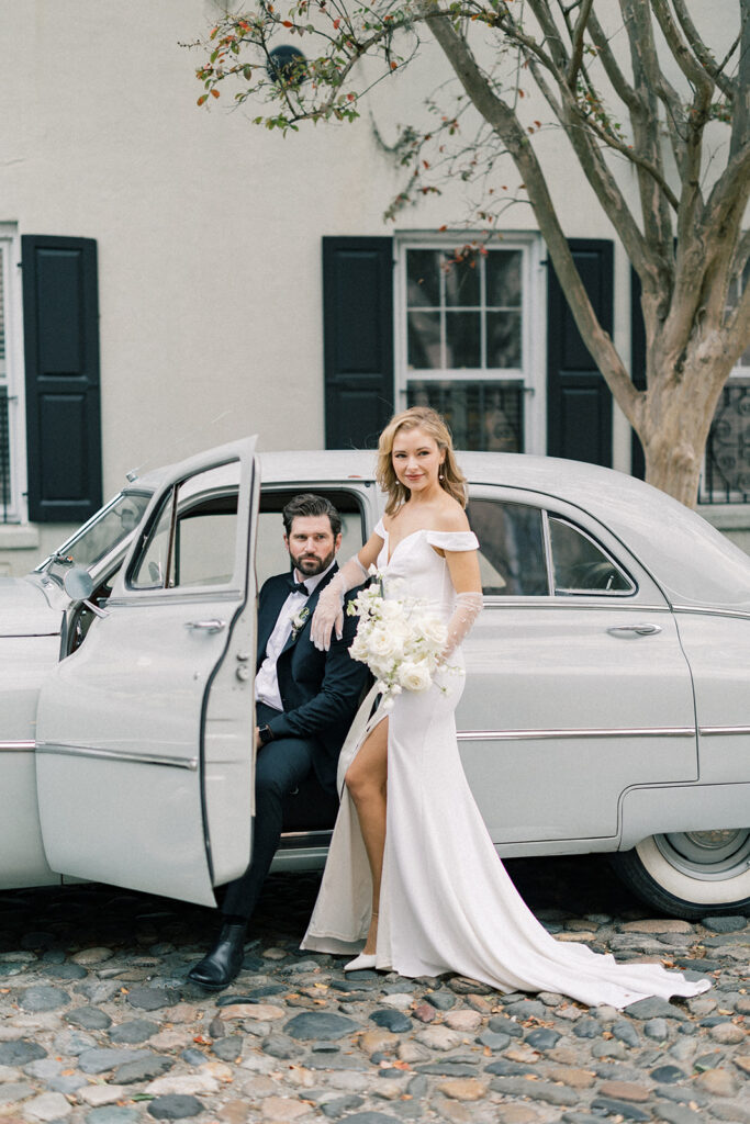 bride and groom posing with vintage car in the french quarter of charleston 
